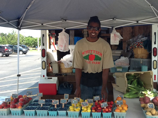 Tomatoes, peppers and squash in quart boxes at the market table