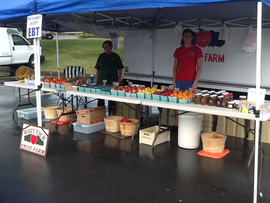 The Whittier Fruit Farm stand under a blue canopy